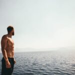 man wearing black shorts standing near ocean