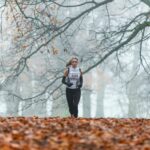 running woman under bare tree during daytime