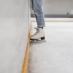 person wearing white and gray skate shoes inside ice skating rink